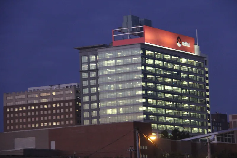 Red Hat Tower in downtown Raleigh at dusk, with the red Red Hat logo lit at the top of the building