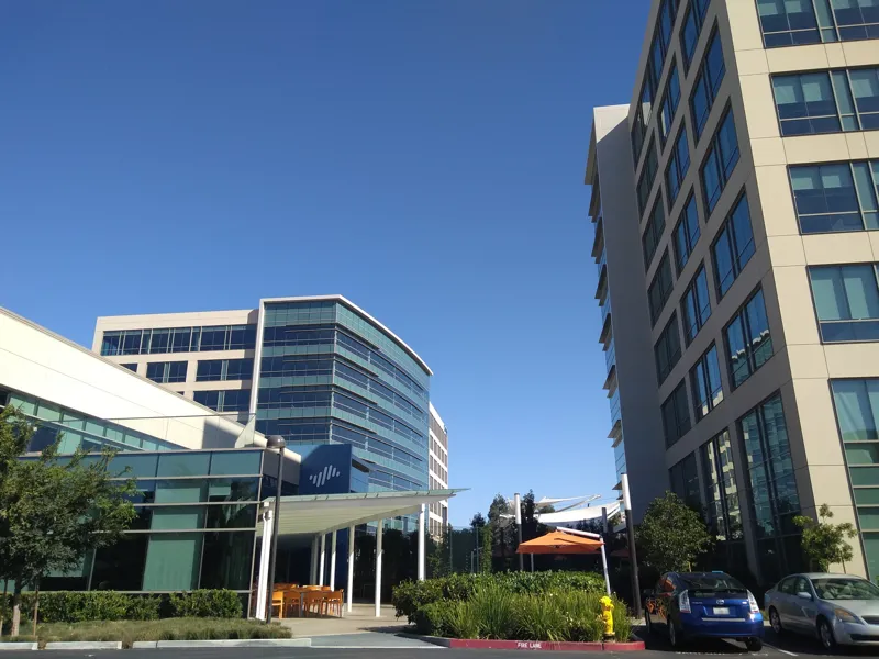 Glass-fronted office buildings of the Palo Alto Networks headquarters campus in Santa Clara under a blue sky, with the company logo on a panel